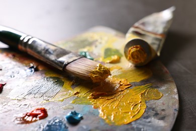 Artist's palette, brush and paints on grey table, closeup