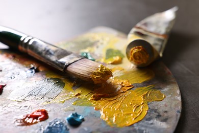 Photo of Artist's palette, brush and paints on grey table, closeup