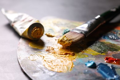 Photo of Artist's palette, brush and paints on grey table, closeup