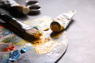 Photo of Artist's palette, brush and paints on grey table, closeup