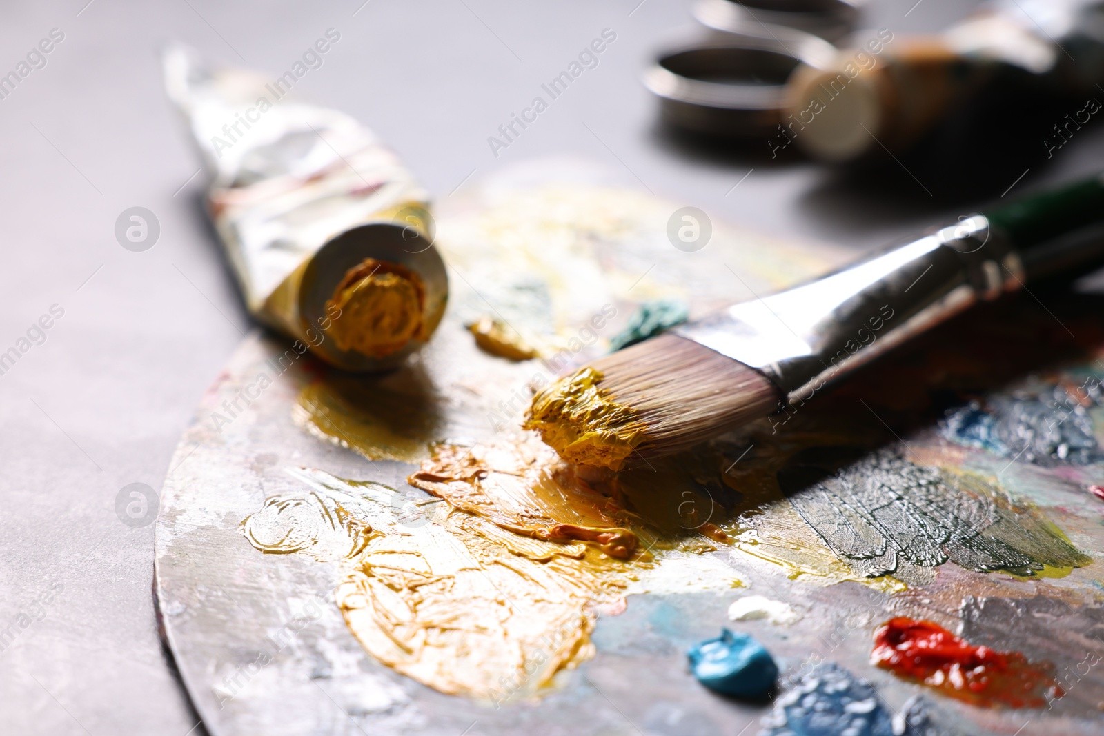 Photo of Artist's palette, brush and paints on grey table, closeup