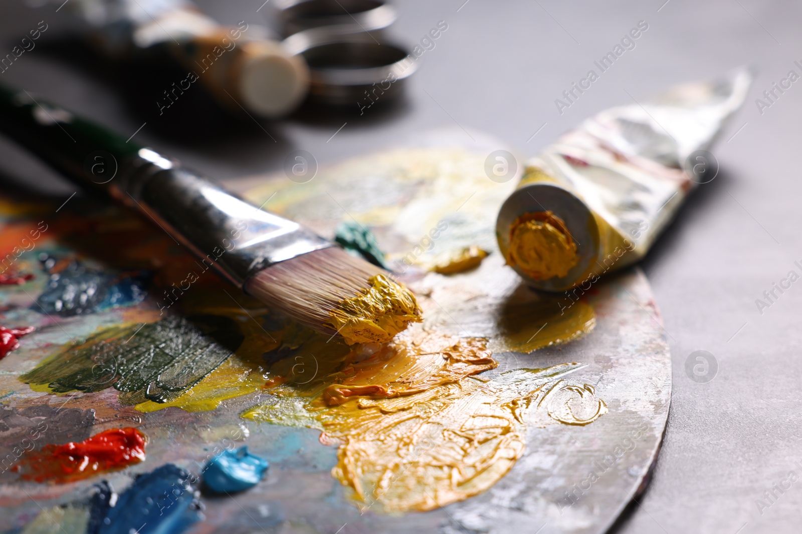 Photo of Artist's palette, brush and paints on grey table, closeup