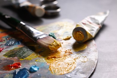 Artist's palette, brush and paints on grey table, closeup