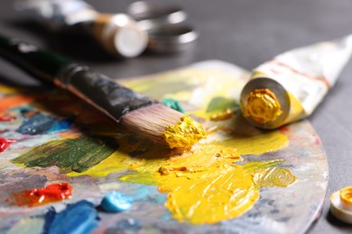 Artist's palette, brush and paints on grey table, closeup