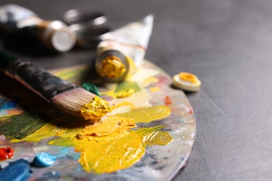 Photo of Artist's palette, brush and paints on grey table, closeup. Space for text