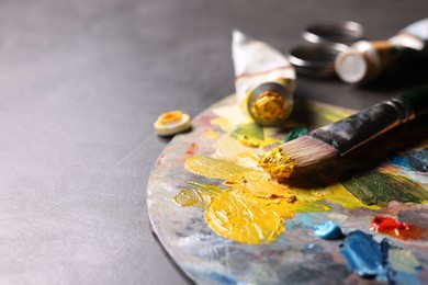 Artist's palette, brush and paints on grey table, closeup. Space for text