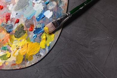 Photo of Artist's palette, brush and paints on grey table, top view. Space for text
