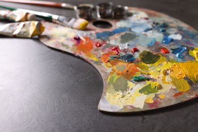 Photo of Artist's palette, brushes and paints on grey table, closeup. Space for text