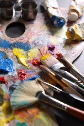 Photo of Artist's palette, brushes and paints on grey table, closeup