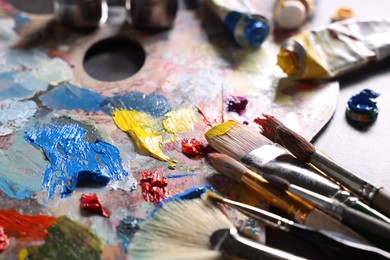 Artist's palette, brushes and paints on grey table, closeup