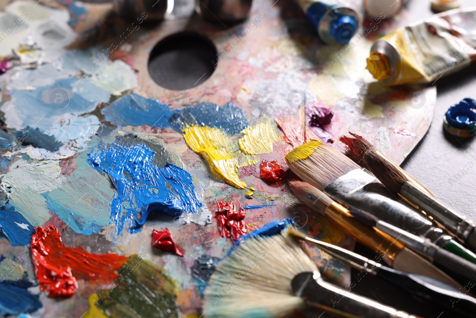 Photo of Artist's palette, brushes and paints on grey table, closeup