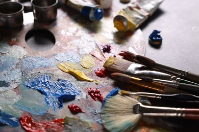 Artist's palette, brushes and paints on grey table, closeup