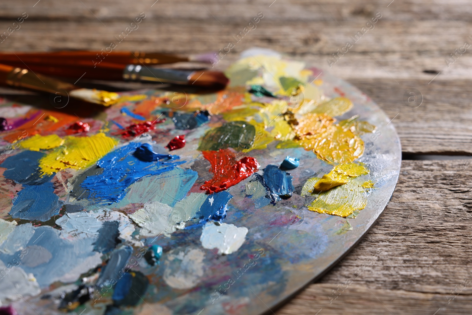 Photo of Artist's palette, brushes and paints on wooden table, closeup