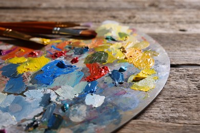 Artist's palette, brushes and paints on wooden table, closeup