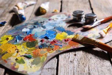 Photo of Artist's palette, brushes and paints on wooden table, closeup