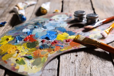 Artist's palette, brushes and paints on wooden table, closeup