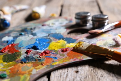 Artist's palette, brushes and paints on wooden table, closeup