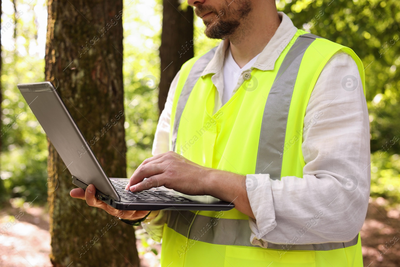 Photo of Forester with laptop working in forest, closeup
