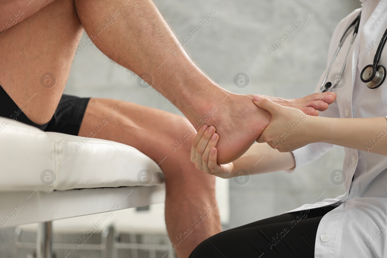 Photo of Sports injury. Doctor examining patient's foot in hospital, closeup