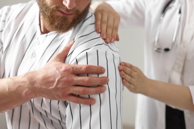 Photo of Sports injury. Doctor examining patient's shoulder in hospital, closeup