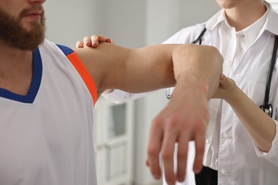 Photo of Sports injury. Doctor examining patient's hand in hospital, closeup