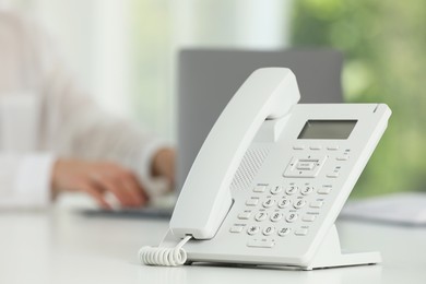 White telephone on table against blurred background, selective focus