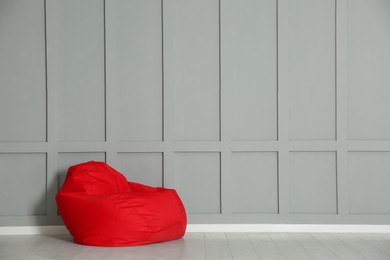 Red bean bag chair near grey wall indoors. Space for text