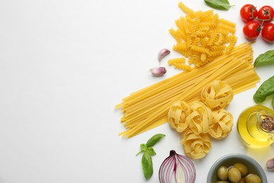 Different types of pasta, spices and products on white background, top view. Space for text