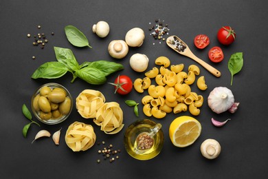 Different types of pasta, spices and products on black background, flat lay