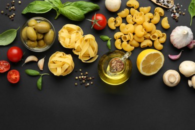 Different types of pasta, spices and products on black background, flat lay