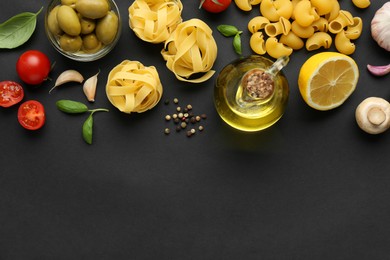 Different types of pasta, spices and products on black background, flat lay. Space for text