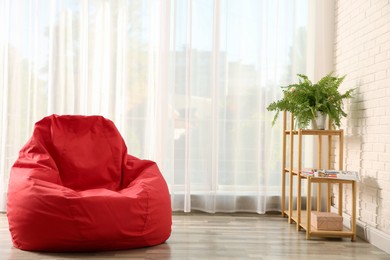 Photo of Red bean bag chair on floor in room. Space for text