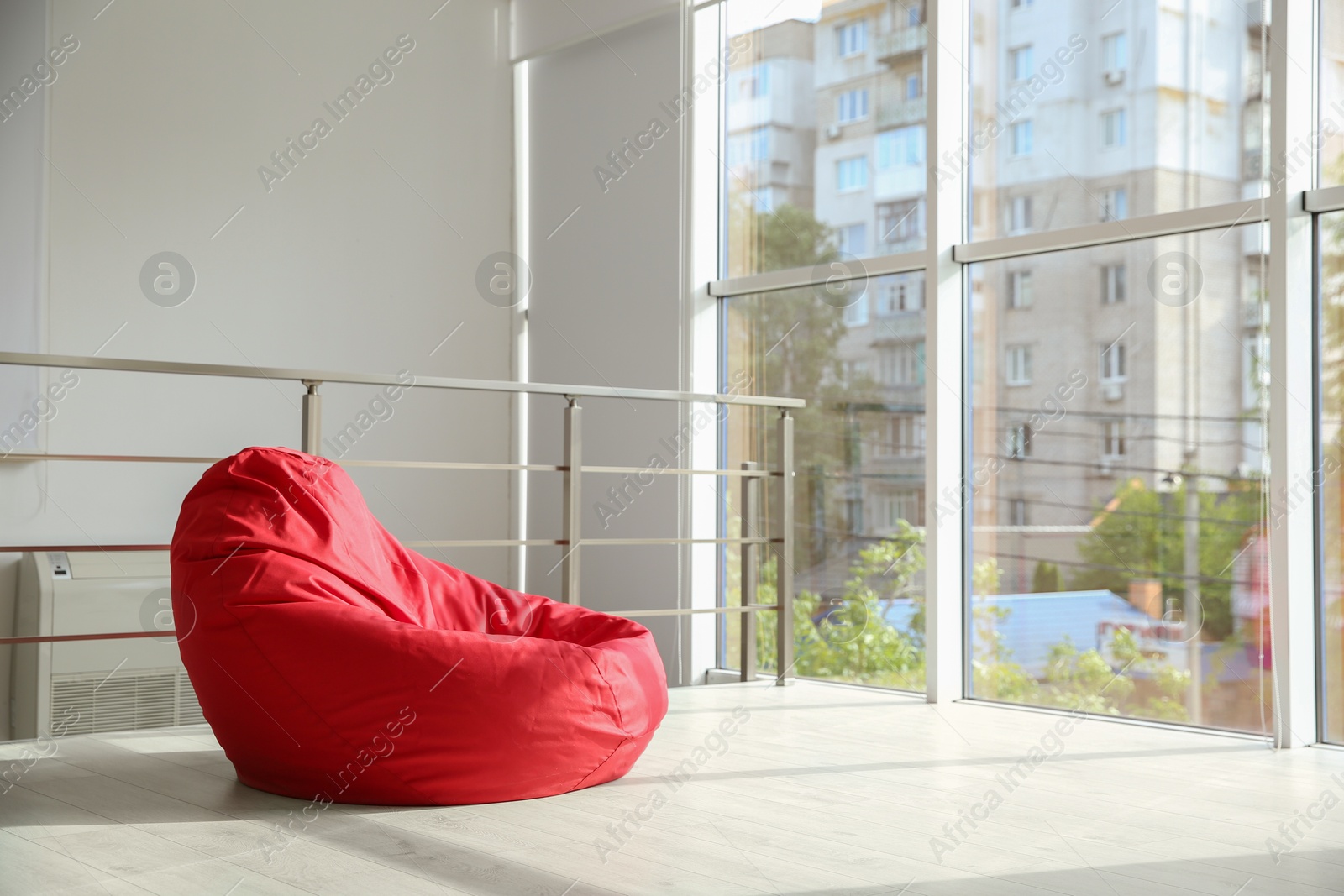 Photo of Red bean bag chair on floor near windows indoors