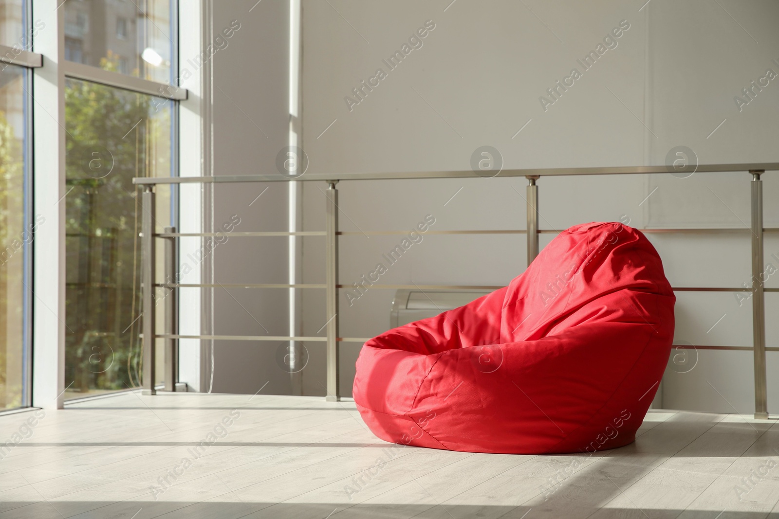 Photo of Red bean bag chair on floor near windows indoors