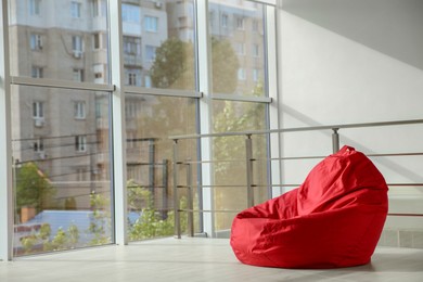 Photo of Red bean bag chair on floor near windows indoors