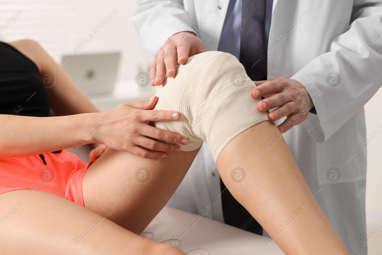 Photo of Sports injury. Doctor examining patient's knee in hospital, closeup