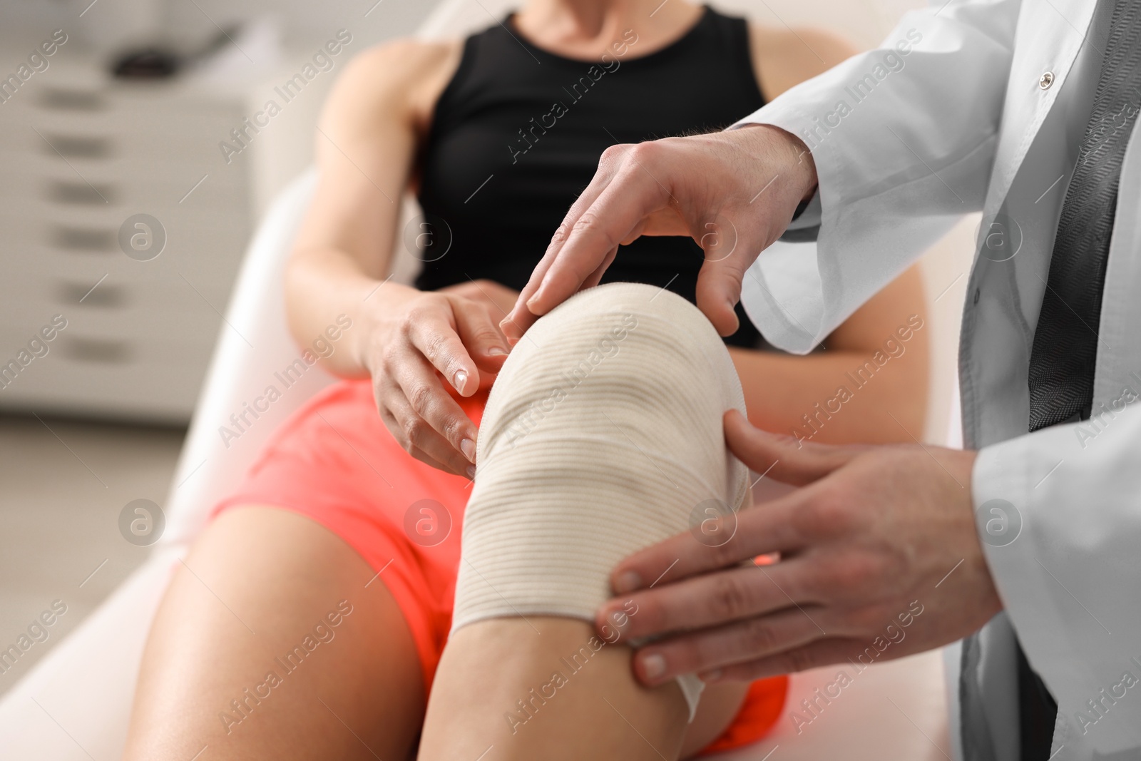 Photo of Sports injury. Doctor examining patient's knee in hospital, closeup