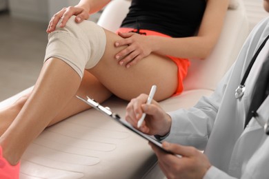 Photo of Sports injury. Doctor with clipboard consulting woman in hospital, closeup