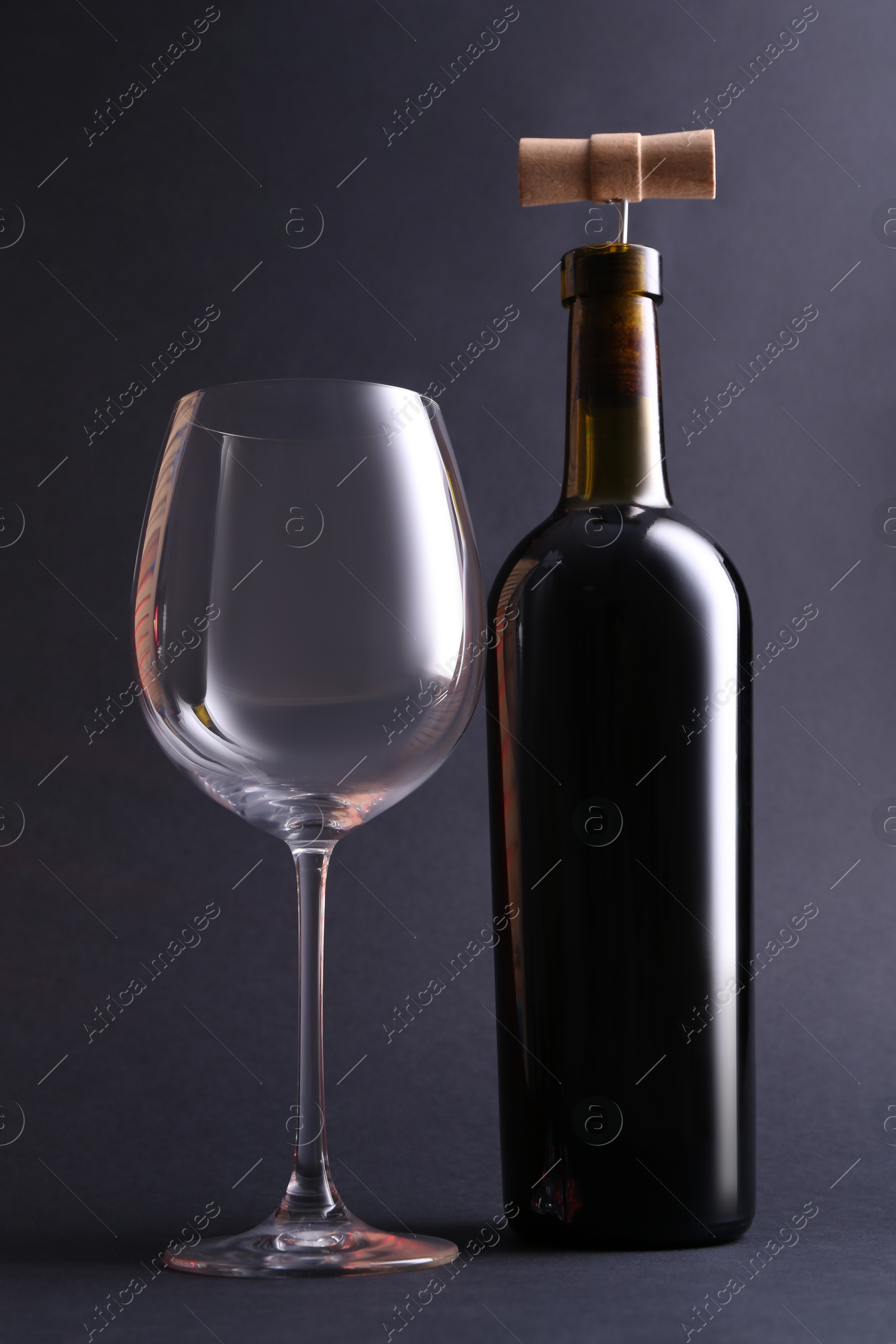 Photo of Wine bottle with corkscrew and glass on grey background