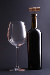 Wine bottle with corkscrew and glass on grey background