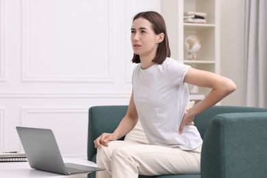 Photo of Woman suffering from back pain at home. Symptom of poor posture