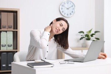 Woman suffering from neck pain in office. Symptom of poor posture