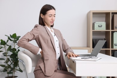 Woman suffering from back pain in office. Symptom of poor posture
