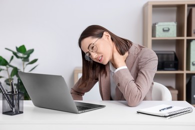 Woman suffering from neck pain in office. Symptom of poor posture