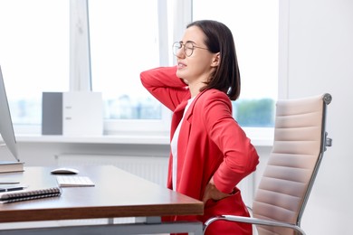 Woman suffering from neck pain in office. Symptom of poor posture