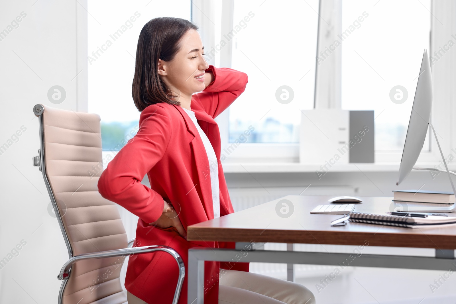 Photo of Woman suffering from neck pain in office. Symptom of poor posture