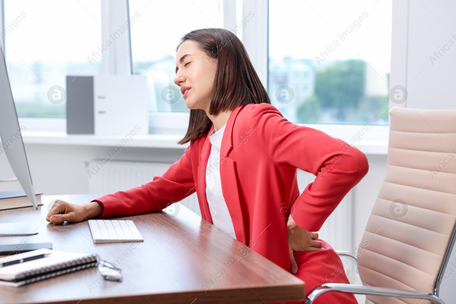 Photo of Woman suffering from back pain in office. Symptom of poor posture