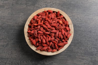 Photo of Dried goji berries in bowl on grey textured table, top view