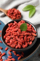 Photo of Dried goji berries in bowl on table, closeup