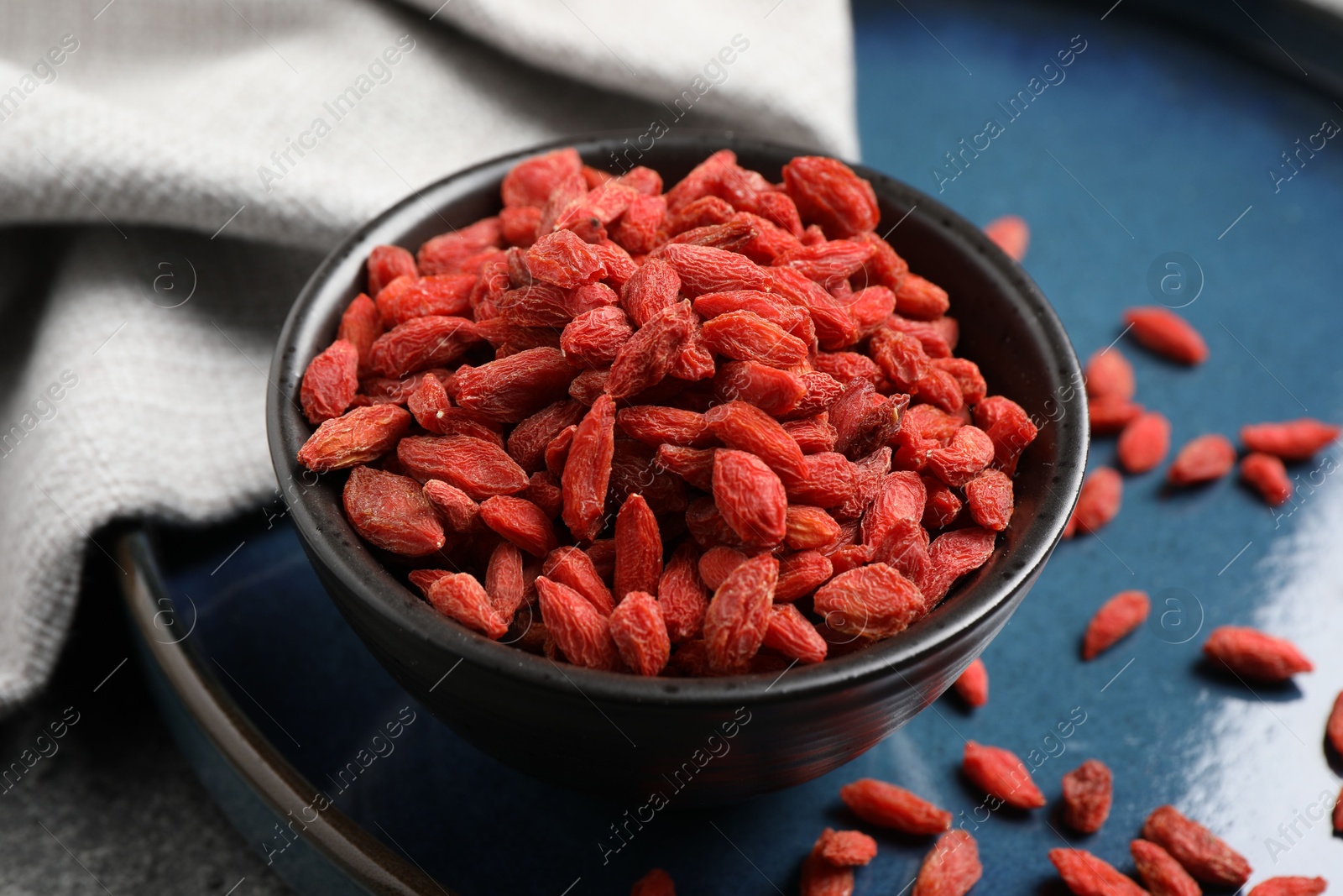 Photo of Dried goji berries in bowl on table, closeup